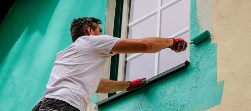 Worker painting the exterior walls of a home